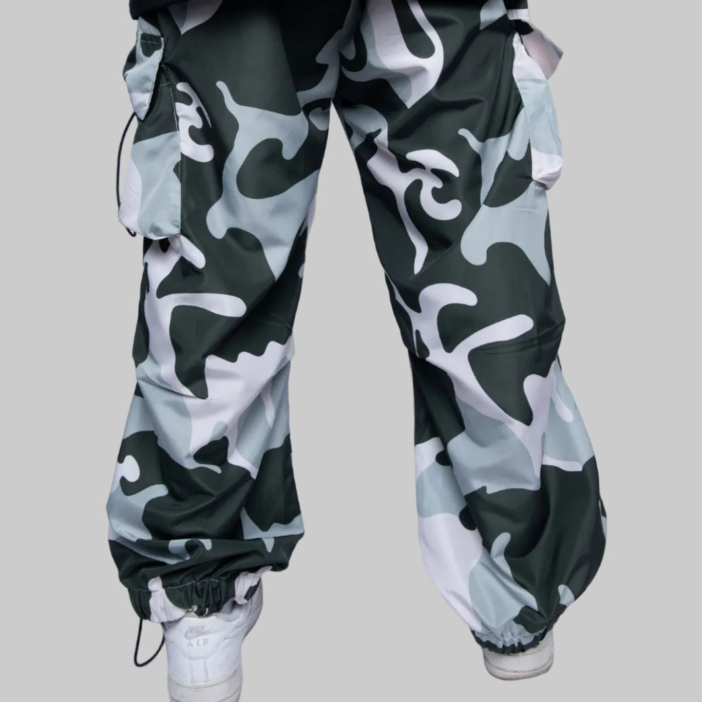 Camouflage pants worn by a person on a white background