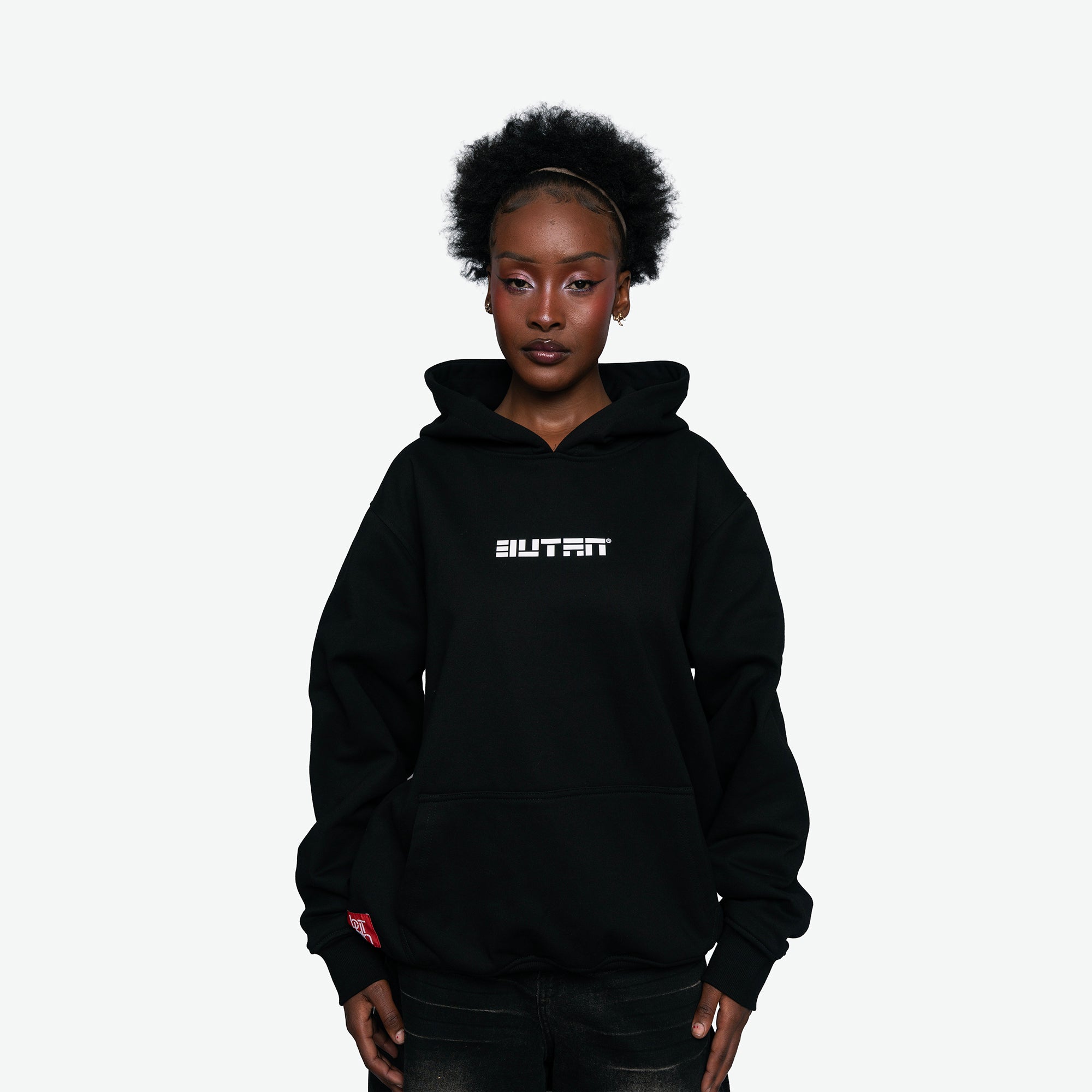 A model wearing a black pullover hoodie with a white 'BUTAN' text graphic on the chest, photographed against a solid light gray background.