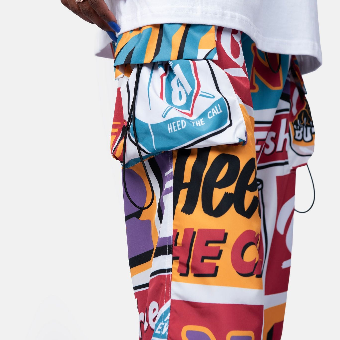 Person wearing a white t-shirt with a colorful graphic design on pants.