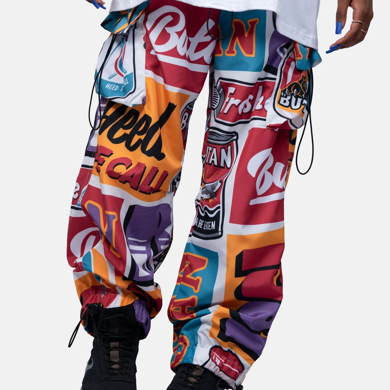 Colorful graphic pants with brand logos worn by a person on a white background