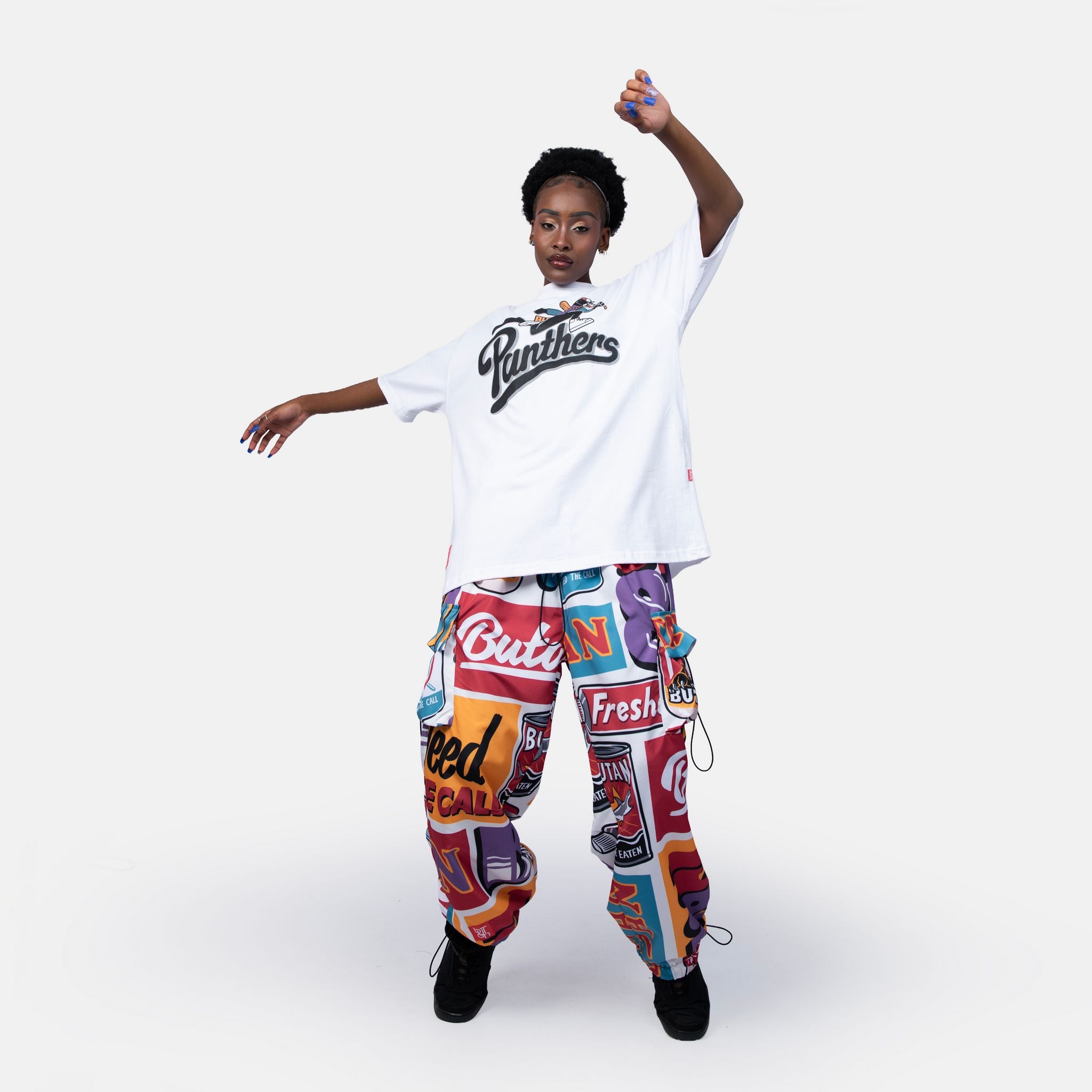 Person wearing a white t-shirt with 'Panthers' text and colorful graphic pants on a white background