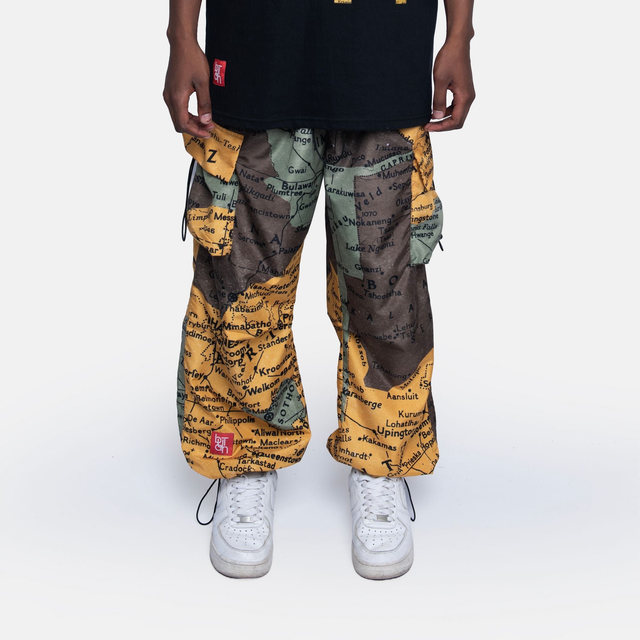 Person wearing colorful map-patterned pants with a plain background