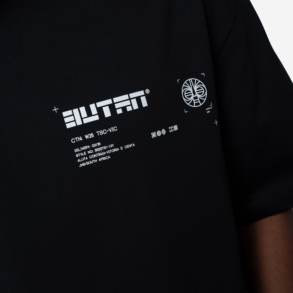 Close-up of a black short-sleeve T-shirt worn by a model, featuring a white graphic print on the chest with the word 'BUTAN' and smaller text.