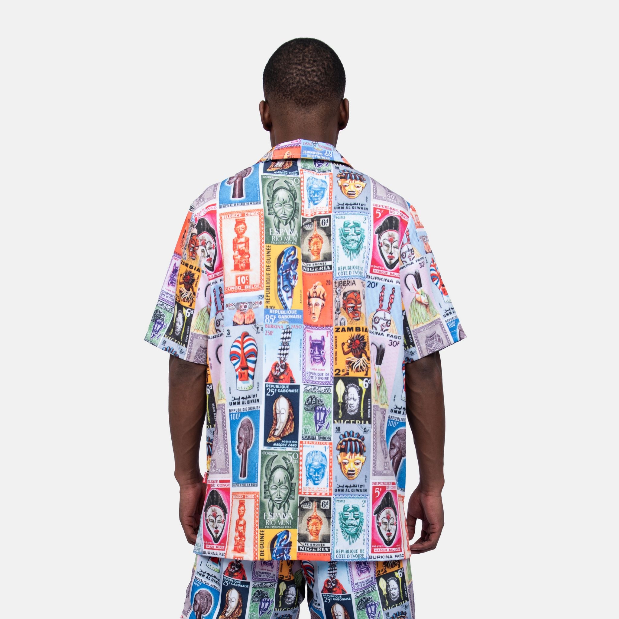 Person wearing a colorful patterned shirt and pants on a white background