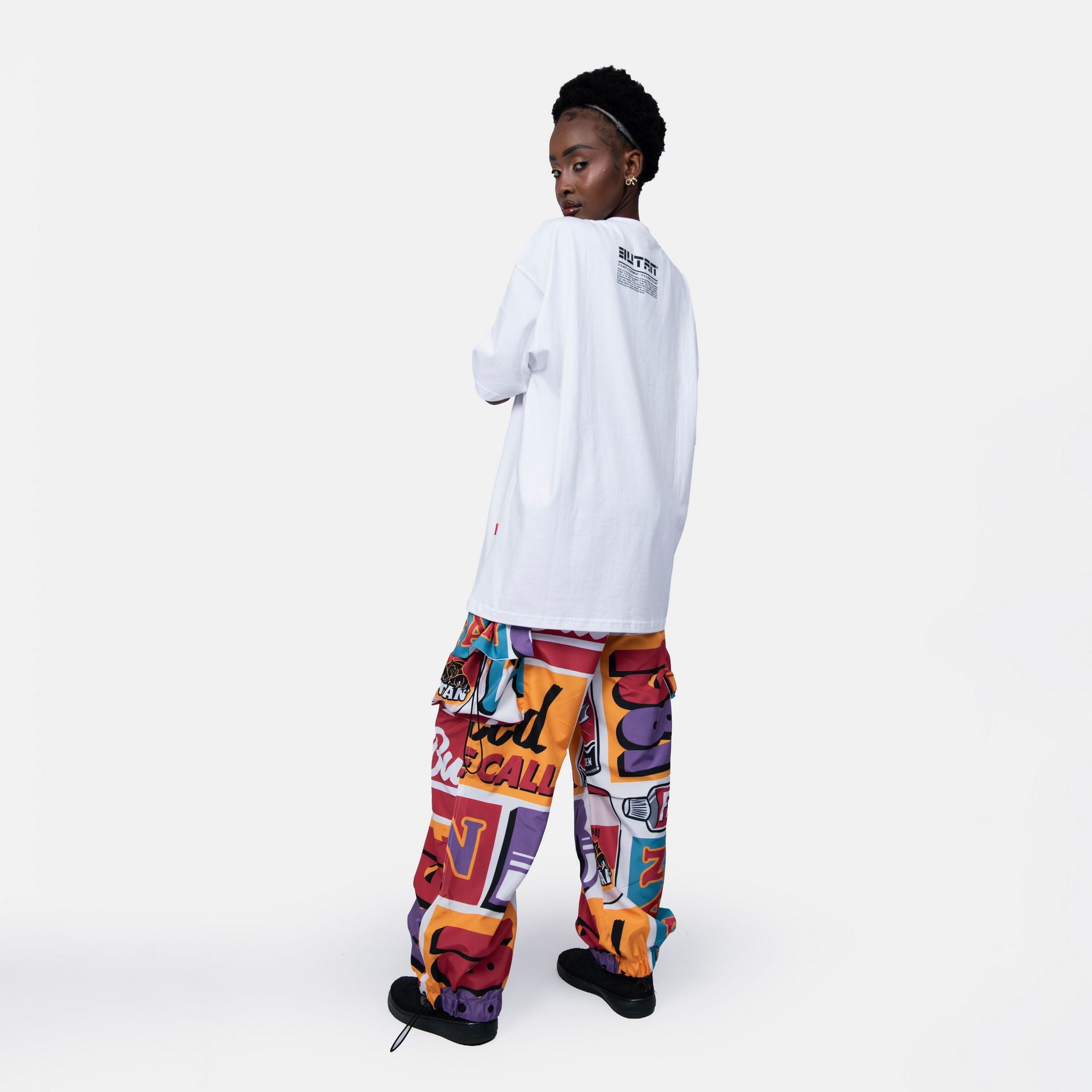 Person wearing a white long-sleeve shirt and colorful pants on a white background