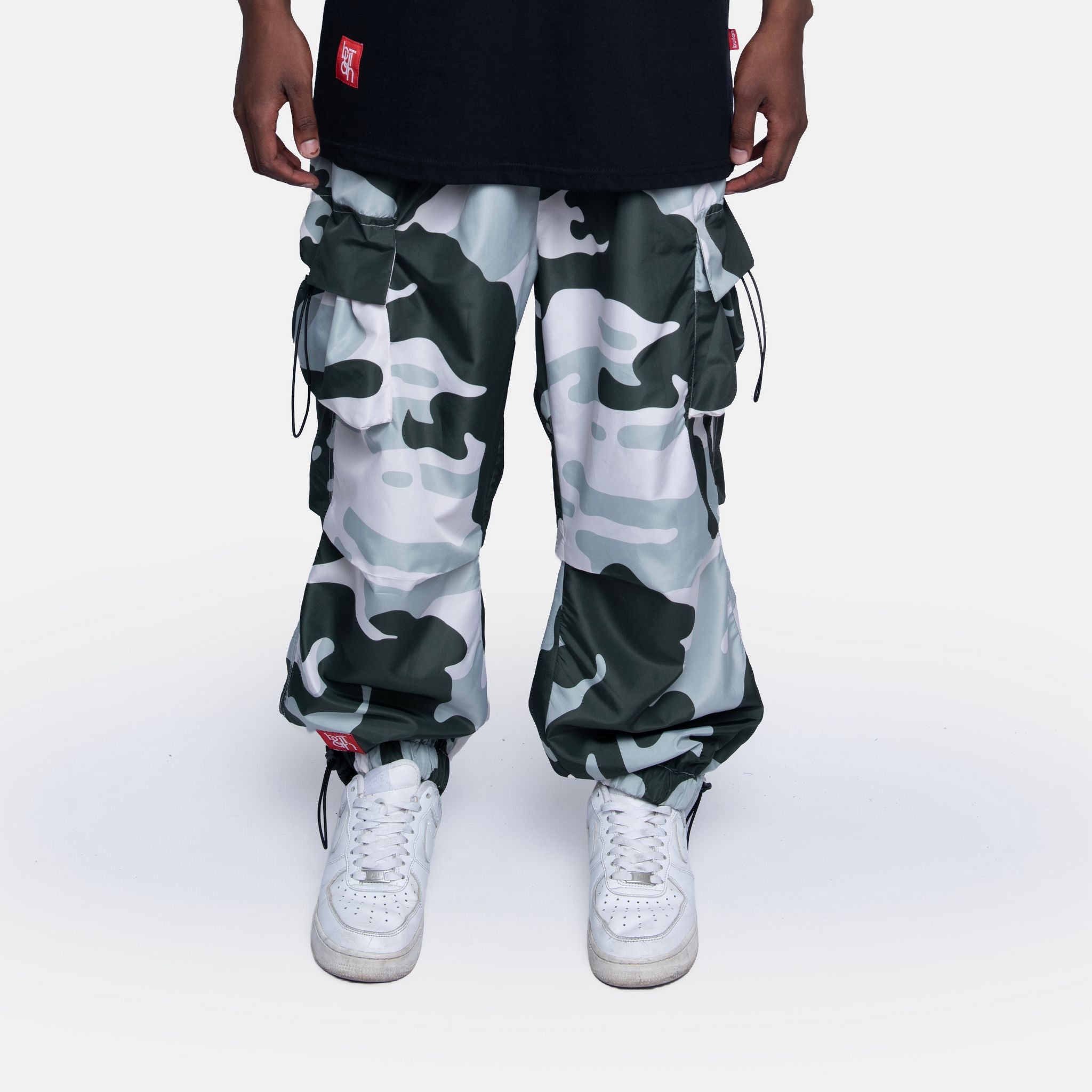 Person wearing camouflage pants and white sneakers on a white background