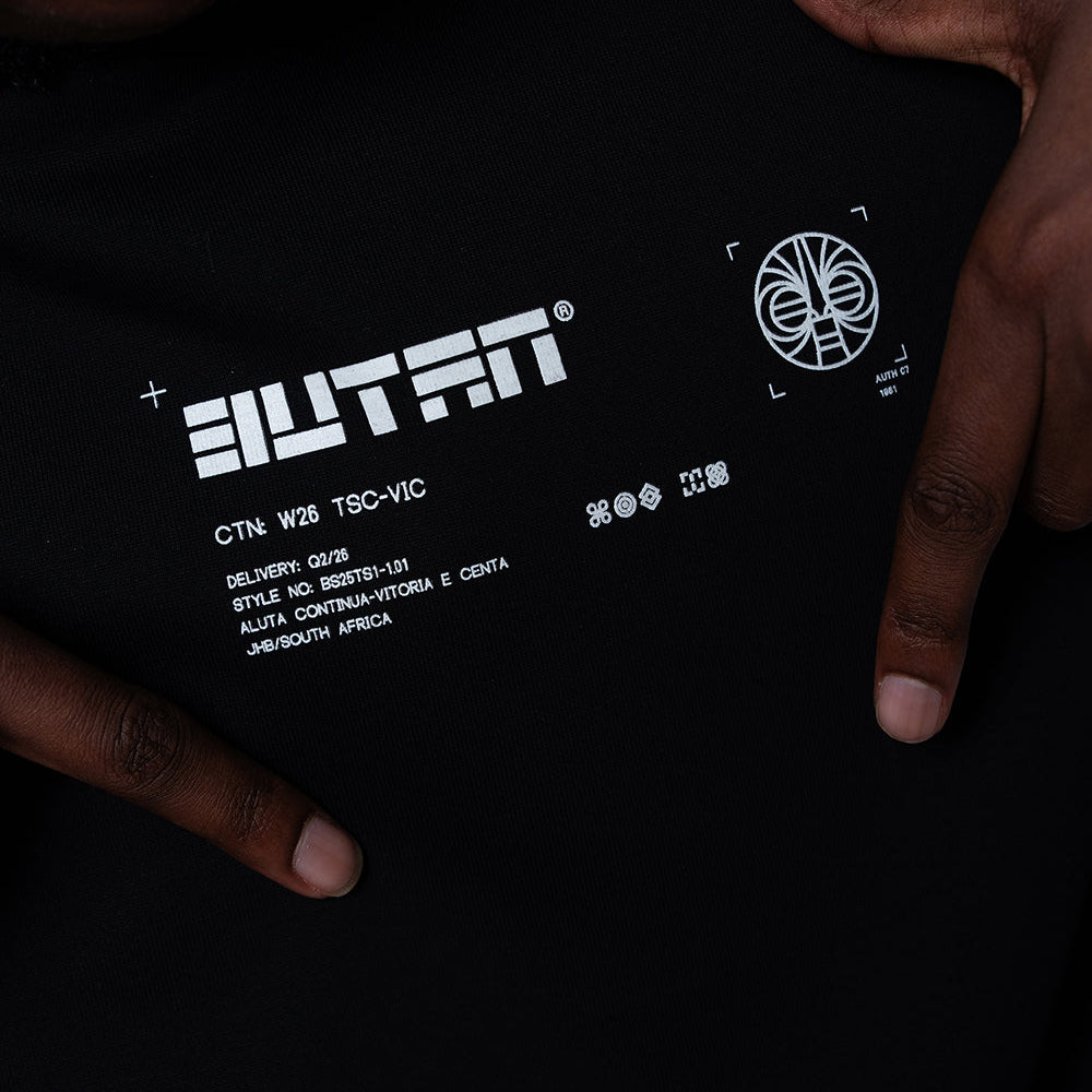 Close-up of a black garment with white printed text and logo, held by two hands. The visible brand text reads 'BUTAN'.
