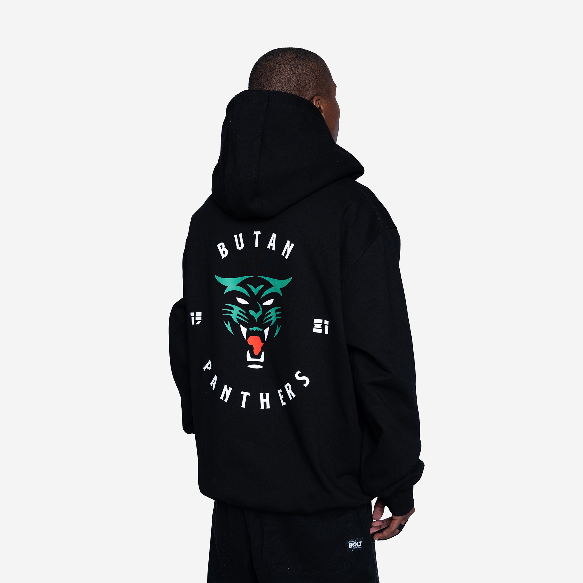 A man shown from the back wearing a black hoodie with a large graphic on the back. The graphic features a green and black panther face with red details, surrounded by the words 'BUTAN PANTHERS' in white and the years '19' and '21'.